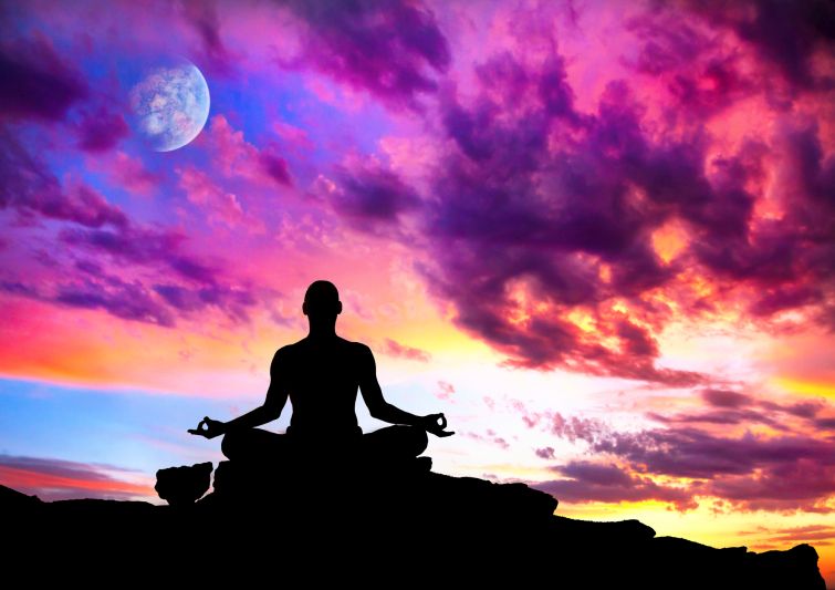 Yoga meditation in lotus pose by man silhouette with moon and purple dramatic sunset sky background. Free space for text and can be used as template for web-sit