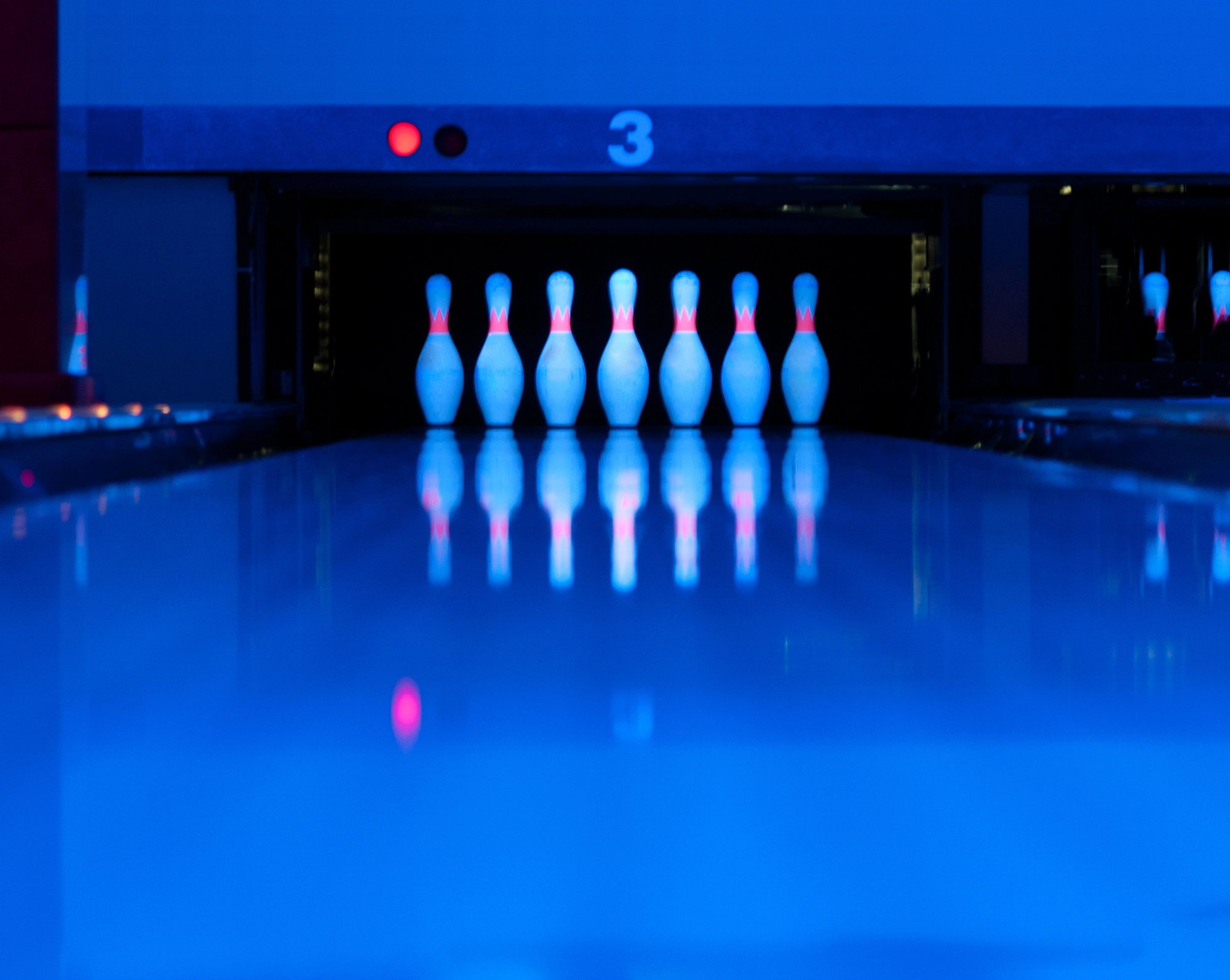 bowling pins set up at the end of an alley illuminated in blacklight